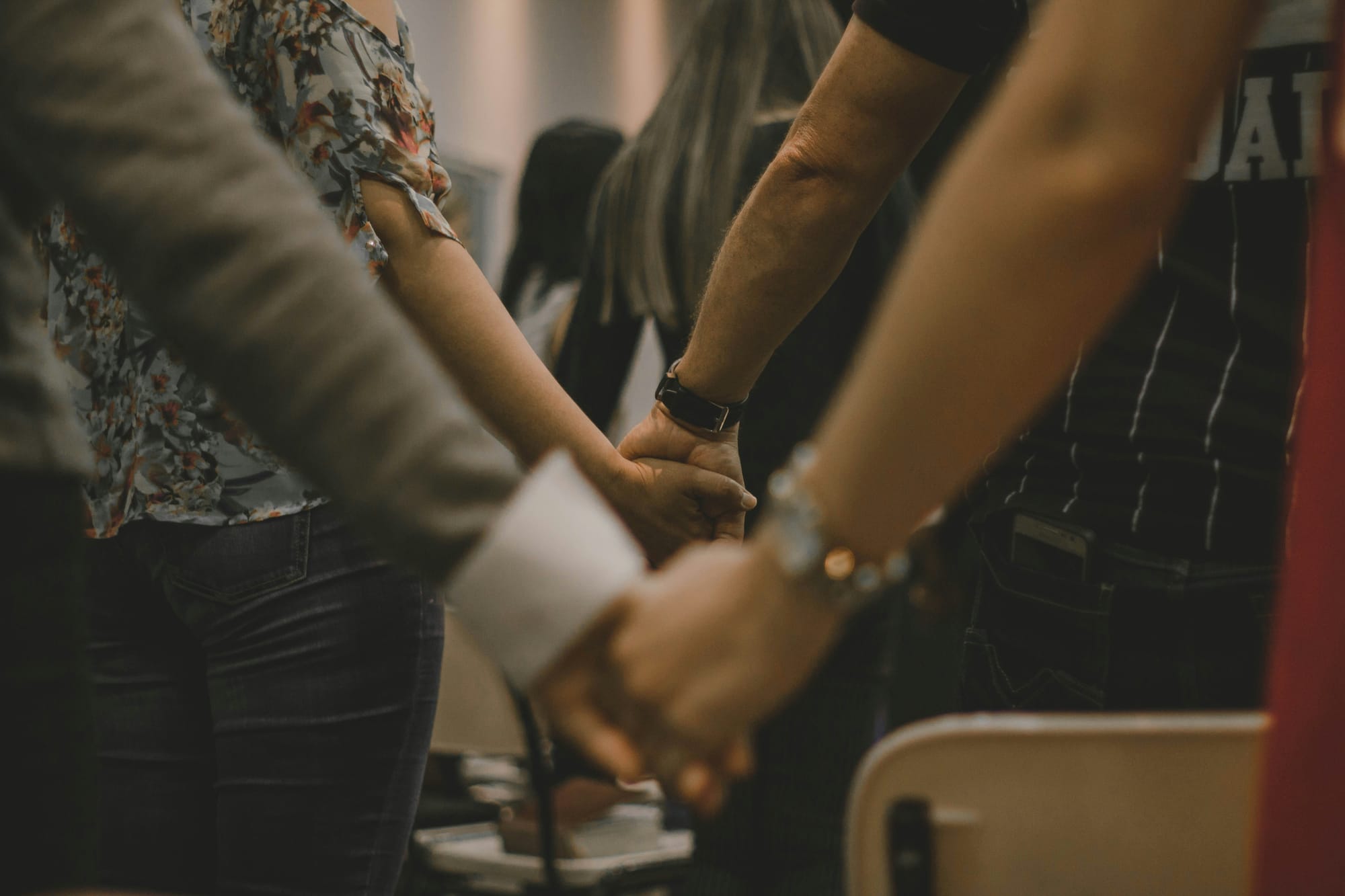 Worshipping people holding hands inside of a room during religious service